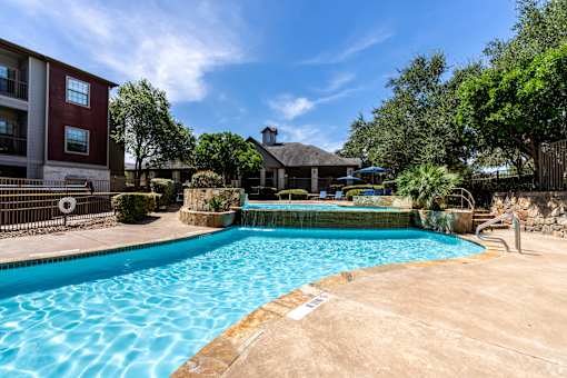 A swimming pool surrounded by a fence and trees.