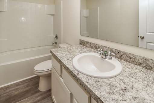 A bathroom with a marble countertop and a white sink.
