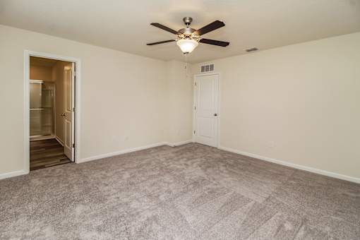 A room with a ceiling fan and carpeted floor.