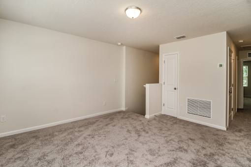 A room with a carpeted floor and a white door.