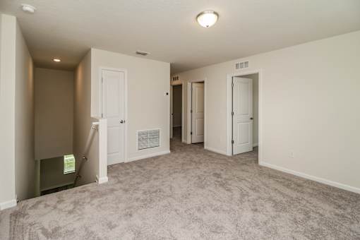 A spacious room with carpeted floor and white walls.