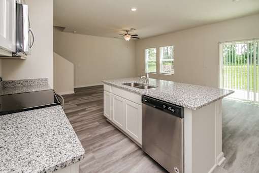 A modern kitchen with a granite countertop and stainless steel appliances.