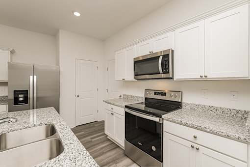 A kitchen with a stainless steel refrigerator, microwave, oven, and sink.