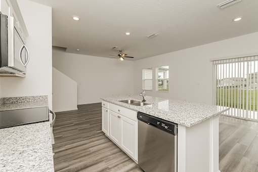 A modern kitchen with a stainless steel dishwasher and a ceiling fan.