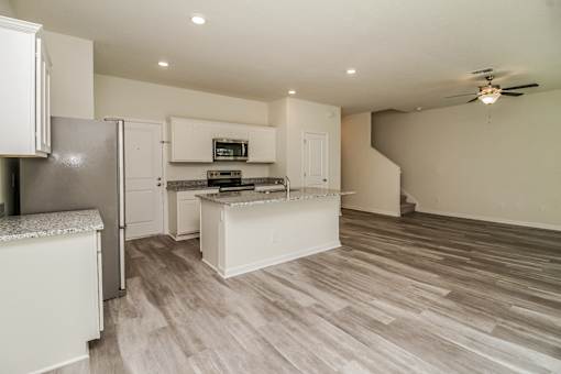 A kitchen with a refrigerator, microwave, and a countertop with a sink.