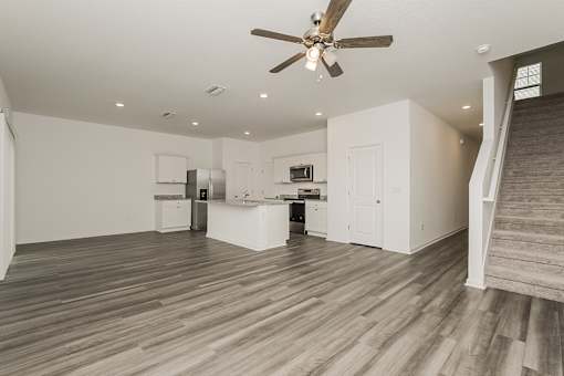 A spacious room with a ceiling fan and wooden flooring.