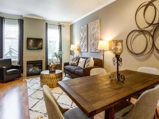 Apartments for Rent in Kenmore, WA - Northshore Townhomes - Furnished Living And Dining Area With Fireplace, Large Windows, Wood Flooring, Sofa Seating, And Decorative Wall Art.