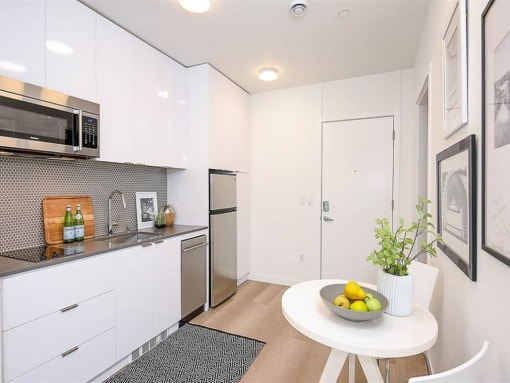 Apartments in Seattle, WA for Rent - Inspire Fremont - Kitchen with a Dining Area, White Modern Cabinets, and Stainless-Steel Appliances