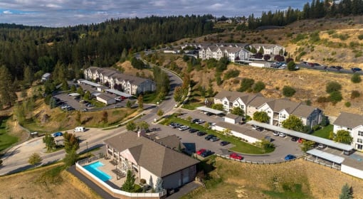Spokane, WA, Apartments for Rent - Canyon Bluffs - Aerial View of Property Exterior Showing Apartment Buildings, Streets, Parking Lots, Pool Area, Grass Fields, and Trees.