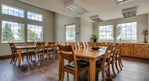 Apartments for Rent Spokane, WA - Deer Creek - Resident Gathering Place with Wood-Style Flooring, Dining Tables, Chairs, and Large Windows.