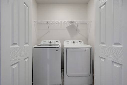 Two white front load washing machines in a small laundry room.