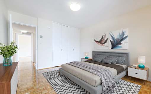A bedroom with a bed, nightstand, and a painting of a bird on the wall.