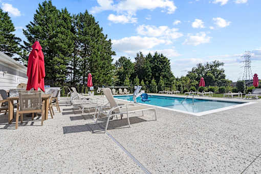 Poolside seating area at Hawks Landing Apartments in Hickory, NC with chairs and umbrellas