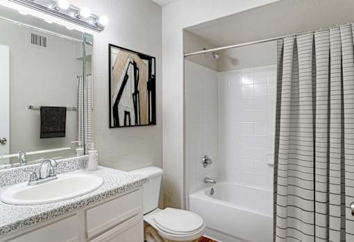 A white bathroom with a toilet, sink, and shower.