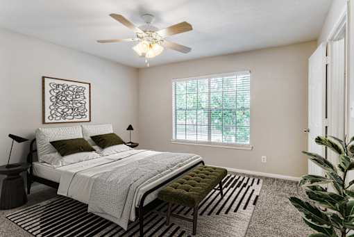 A bedroom with a bed, a bench, and a ceiling fan.