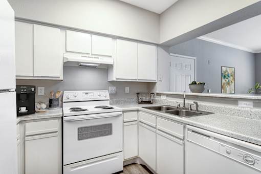 A white kitchen with a stove, sink, and refrigerator.