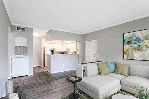 A living room with a white couch and a painting on the wall.