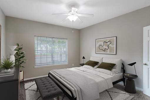 A bedroom with a bed, chair, and ceiling fan.