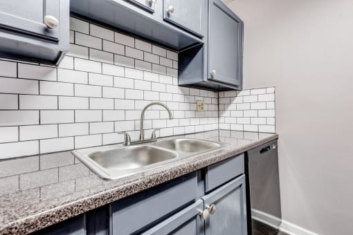 a kitchen with a sink and white subway tiles
