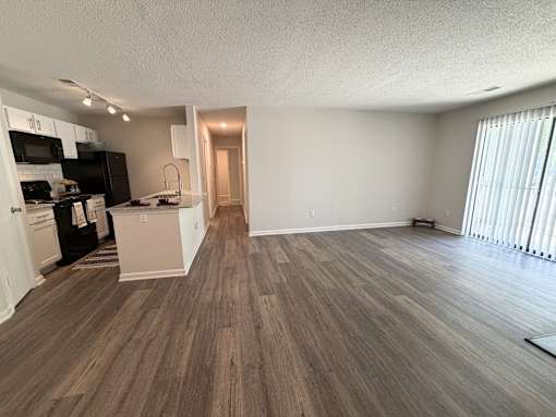 A kitchen with black appliances and a wooden floor.
