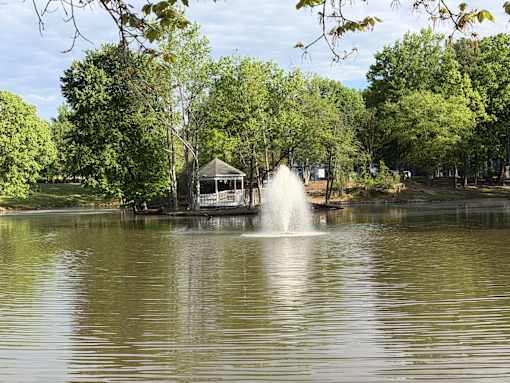 A fountain in the middle of a lake surrounded by trees.