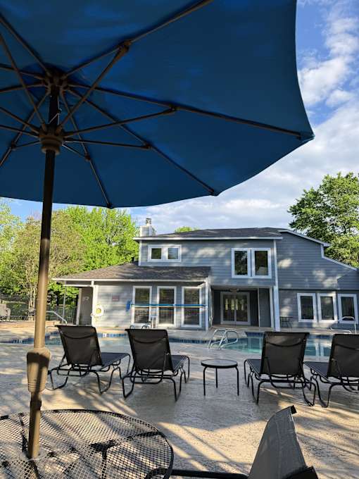 A blue umbrella is casting a shadow over a table and chairs.