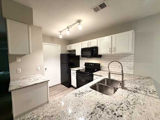 A kitchen with granite countertops and white cabinets.
