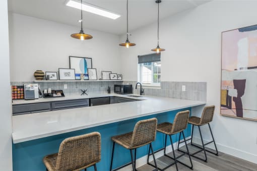 1-Bedroom Apartments in Everett, Washington - Woodbrook - Community Kitchen with Coffee Maker, Microwave, Breakfast Bar with Bar-Style Wicker Chairs, and Pendant Lights.