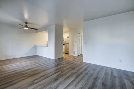 One BR Apartments in Everett Washington - Woodbrook - Empty Living Room with Wood-Style Flooring and Ceiling Fan