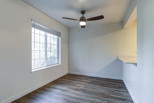 Apartments for Rent in Everett, Washington - Woodbrook - Dining Room with Wood-Style Flooring, Ceiling Fan, and Large Window.