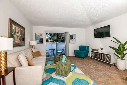 a living room with a couch and a tv and a door to a balcony