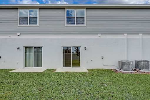 A house with a grey roof and white walls with a green lawn in front.
