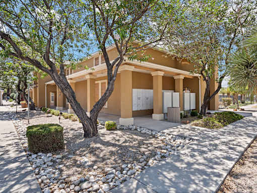 A beige house with a tree in front.