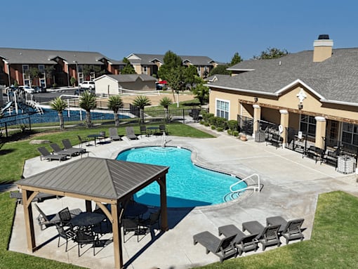 A pool with a table and chairs is surrounded by a fence.
