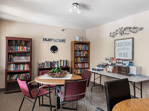 A room with a table, chairs, and bookshelves.