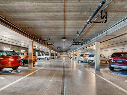 A parking garage with cars parked on both sides of the aisle.