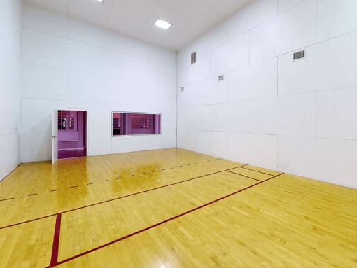 a Raquetball court with a wooden floor and white walls