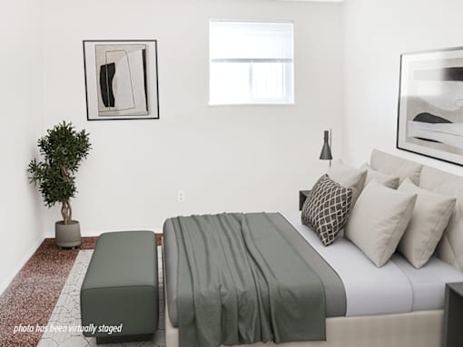 A bedroom with a bed, a bench, and a potted plant.