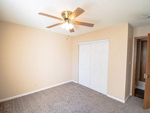 A room with a ceiling fan and a white door.