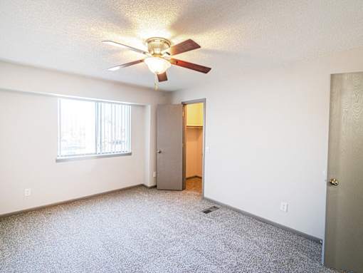 A room with a ceiling fan and a door.