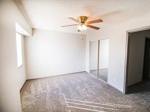 A room with a ceiling fan and carpeted floor.