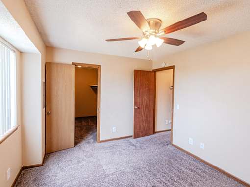 A room with a ceiling fan and carpeted floor.