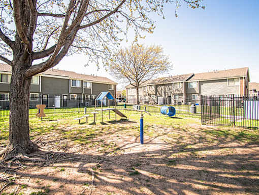A playground area with a swing set and a slide in front of apartment buildings.