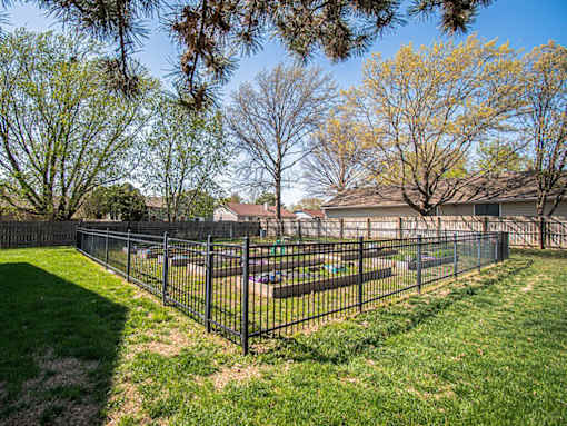 A black fence surrounds a green lawn.