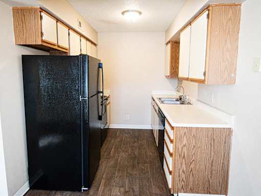 A black fridge in a kitchen with wooden cabinets.