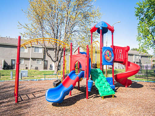 A playground with a red and blue slide and a yellow arch.