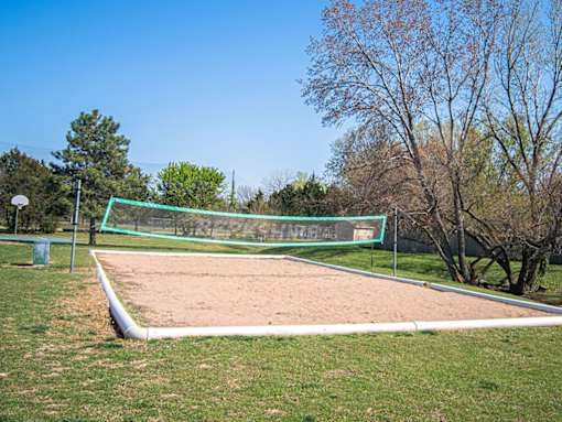 A sand volleyball court with a green net and white boundary lines.