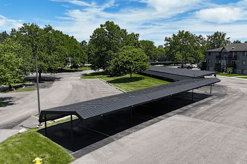 A black covered walkway leads from a parking lot to a building.