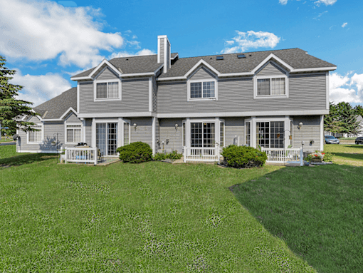 A large house with a grey roof and a white fence.