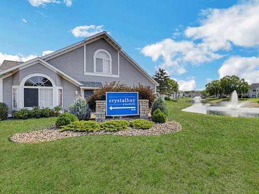 A blue sign with the word "crystalbay" on it is in front of a house.